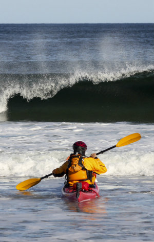 Sea Kayaker heads out through surf Sea Kayaker heads out through surf